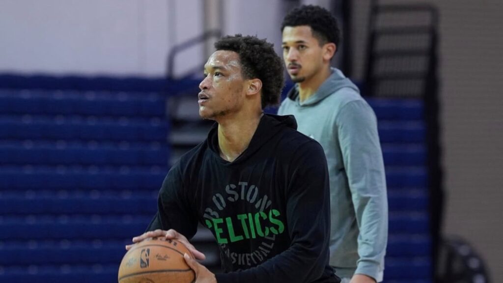 Boaz Mensah (achtergrond) kijkt toe bij een training Wendell Moore jr. 
